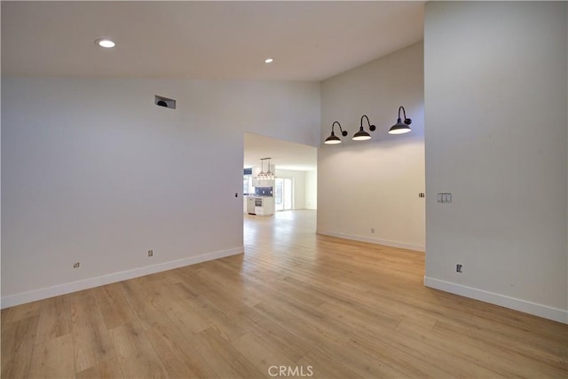 empty room featuring high vaulted ceiling and light wood-type flooring