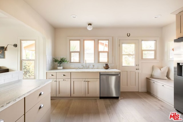 kitchen with appliances with stainless steel finishes, decorative backsplash, light hardwood / wood-style flooring, and sink