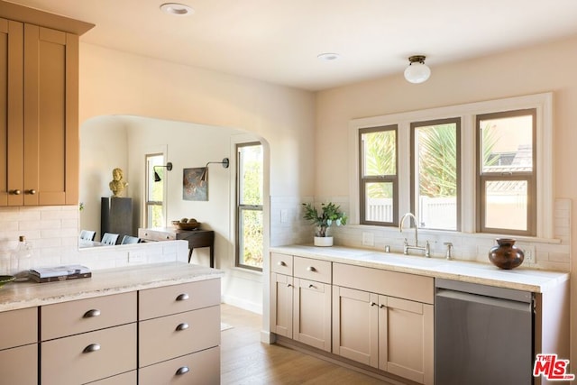 kitchen with dishwasher, decorative backsplash, sink, light hardwood / wood-style flooring, and light stone countertops