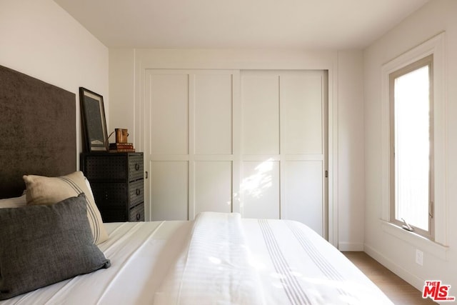 bedroom with a closet, multiple windows, and light hardwood / wood-style floors