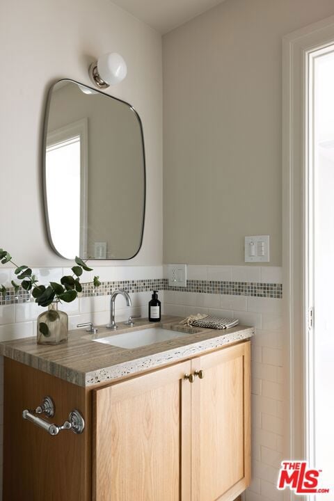 bathroom with vanity and tile walls