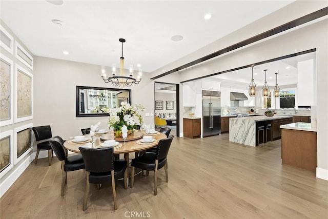 dining space featuring light wood-type flooring and an inviting chandelier