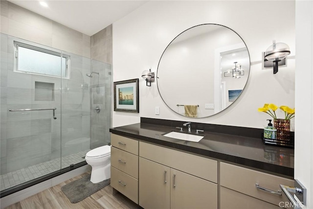 bathroom featuring walk in shower, vanity, wood-type flooring, and toilet