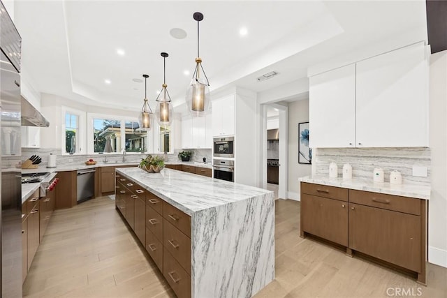 kitchen featuring stainless steel dishwasher, white cabinets, a tray ceiling, and a kitchen island