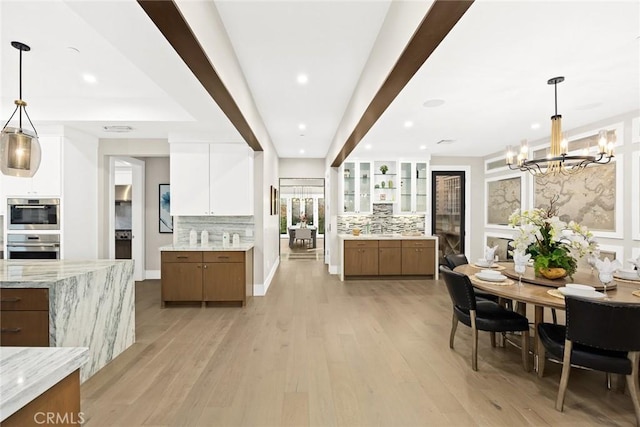 kitchen featuring white cabinetry, light hardwood / wood-style flooring, a notable chandelier, and hanging light fixtures