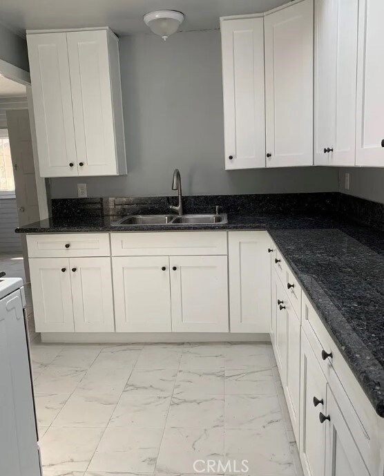 kitchen with white cabinets, dark stone countertops, and sink