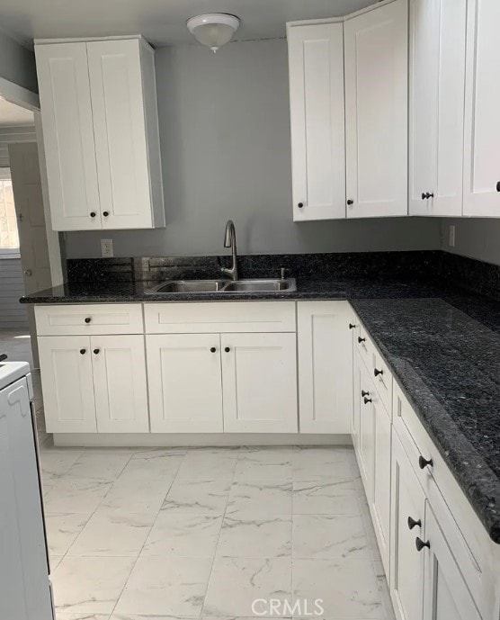 kitchen featuring dark stone counters, sink, and white cabinetry