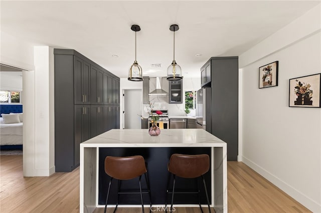 kitchen featuring plenty of natural light, wall chimney range hood, stainless steel stove, and light wood-type flooring