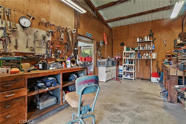 miscellaneous room featuring vaulted ceiling, concrete floors, wood walls, and a workshop area