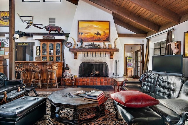 living room featuring a brick fireplace, vaulted ceiling with beams, bar, ceiling fan, and wooden ceiling