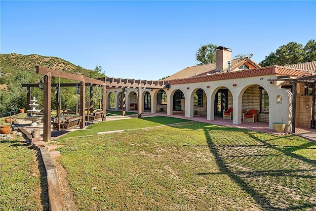 rear view of property featuring a patio area, a mountain view, and a yard