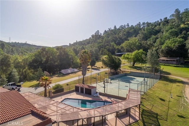 view of swimming pool featuring tennis court and a yard