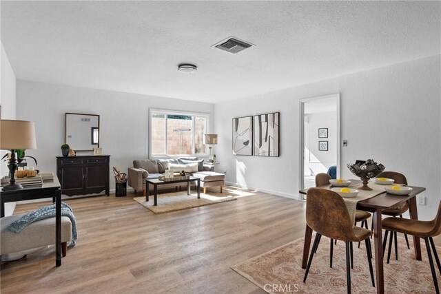 dining space with light wood-type flooring and a textured ceiling