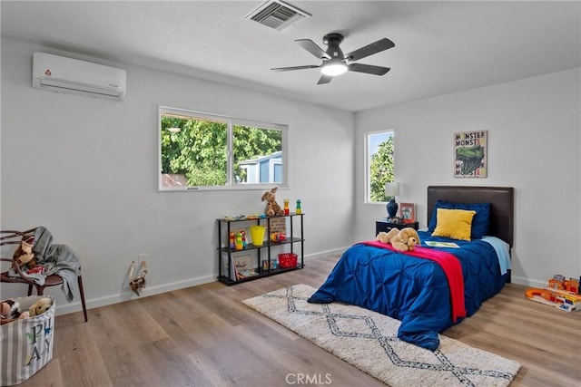 bedroom with ceiling fan, light hardwood / wood-style floors, and a wall unit AC