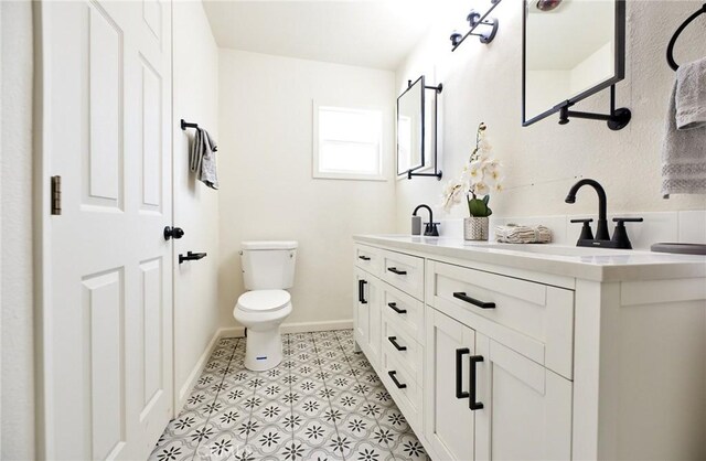 bathroom with toilet, vanity, and tile patterned flooring