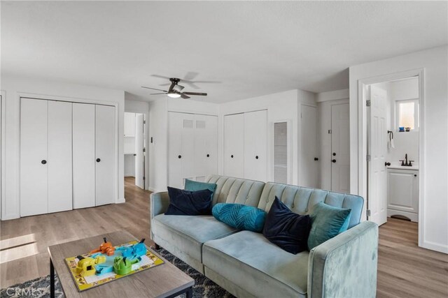 living room with ceiling fan, sink, and light hardwood / wood-style floors