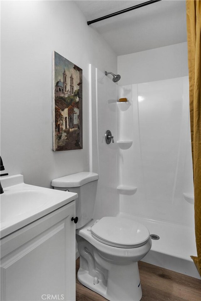 bathroom with hardwood / wood-style flooring, curtained shower, toilet, and vanity