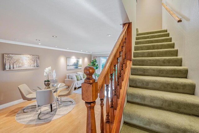 stairs featuring ornamental molding and wood-type flooring