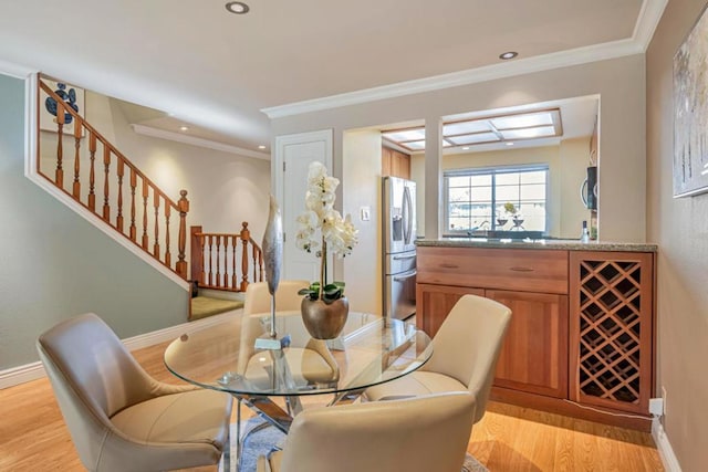 dining space with crown molding and light hardwood / wood-style flooring