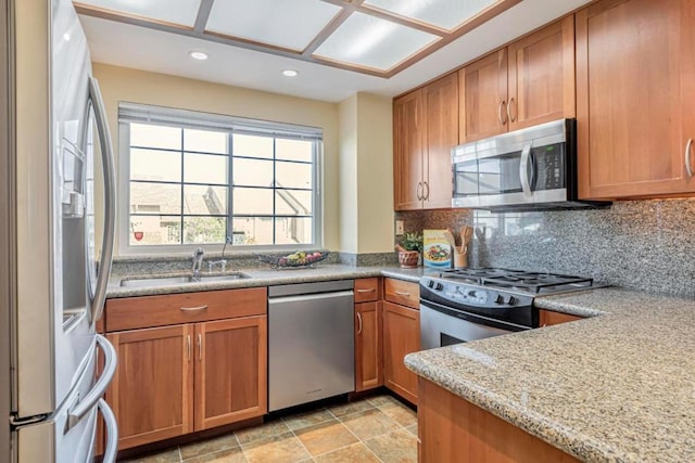 kitchen with light stone counters, sink, stainless steel appliances, and tasteful backsplash