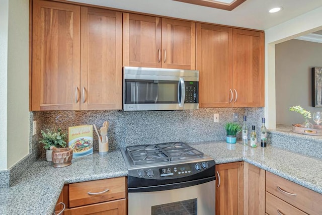 kitchen featuring appliances with stainless steel finishes, light stone counters, and tasteful backsplash