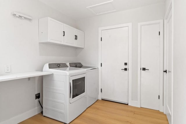 clothes washing area with light wood-type flooring, separate washer and dryer, and cabinets