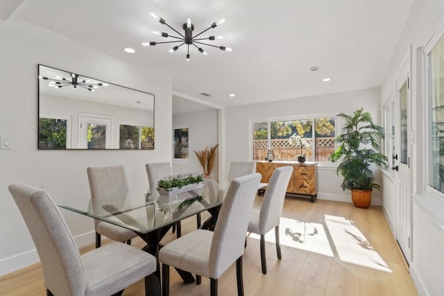 dining space with light hardwood / wood-style floors and a notable chandelier