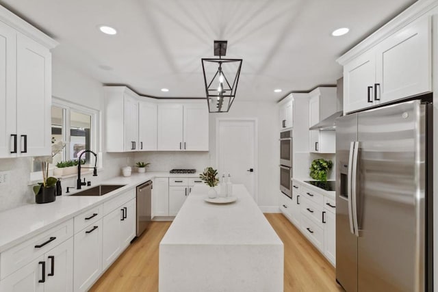 kitchen with appliances with stainless steel finishes, sink, pendant lighting, wall chimney exhaust hood, and a center island