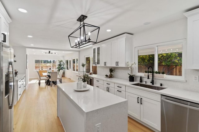 kitchen with decorative light fixtures, a kitchen island, sink, appliances with stainless steel finishes, and white cabinets