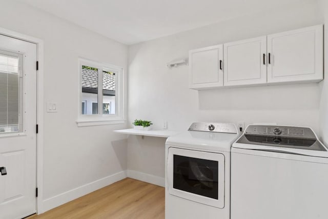 laundry area with cabinets, washer and clothes dryer, and light hardwood / wood-style flooring