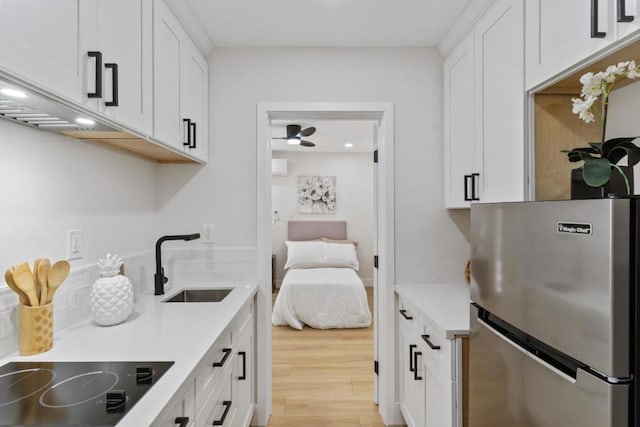 kitchen featuring white cabinets, stainless steel fridge, sink, and black electric cooktop