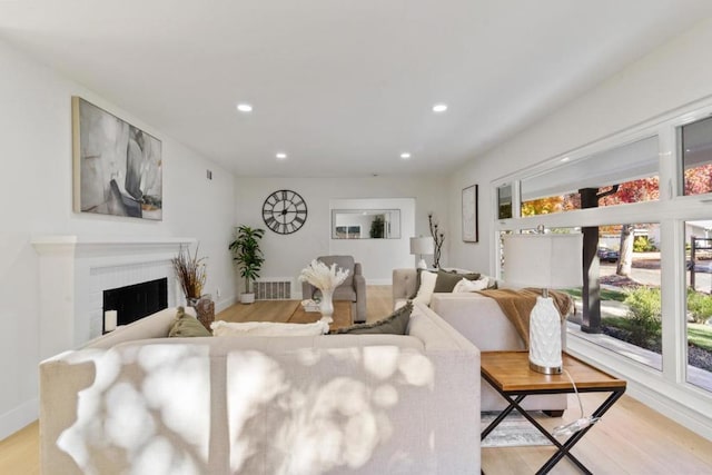 living room with a healthy amount of sunlight, a brick fireplace, and light hardwood / wood-style floors