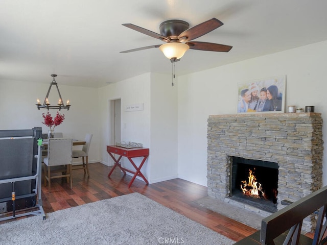 living room featuring a fireplace, dark wood-type flooring, and ceiling fan with notable chandelier