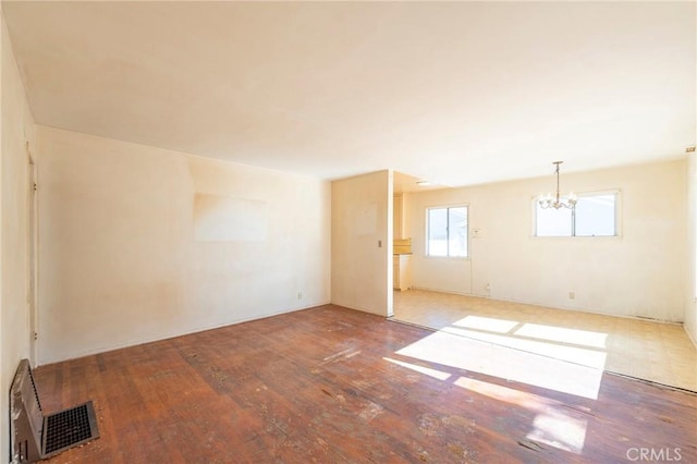 spare room featuring an inviting chandelier and hardwood / wood-style flooring