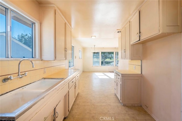 kitchen featuring a chandelier, decorative light fixtures, tasteful backsplash, white cabinets, and sink