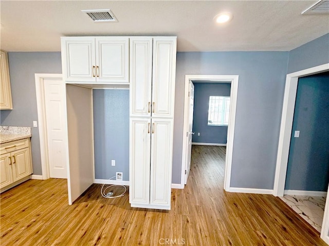 kitchen with light hardwood / wood-style floors and white cabinets