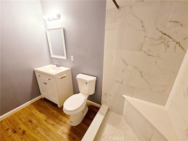 bathroom with toilet, vanity, wood-type flooring, and tiled shower