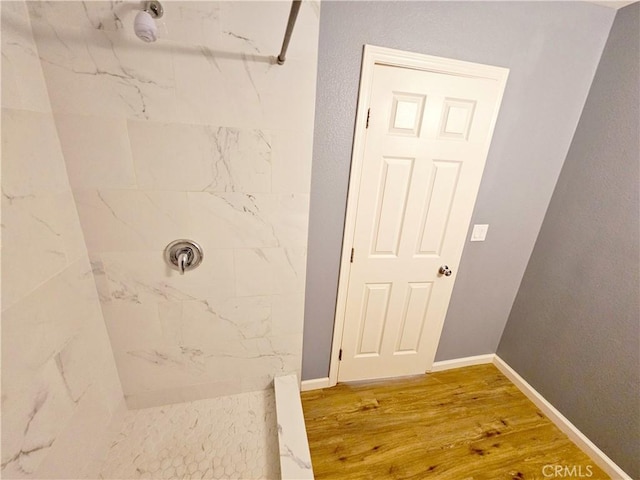 bathroom with a tile shower and hardwood / wood-style flooring