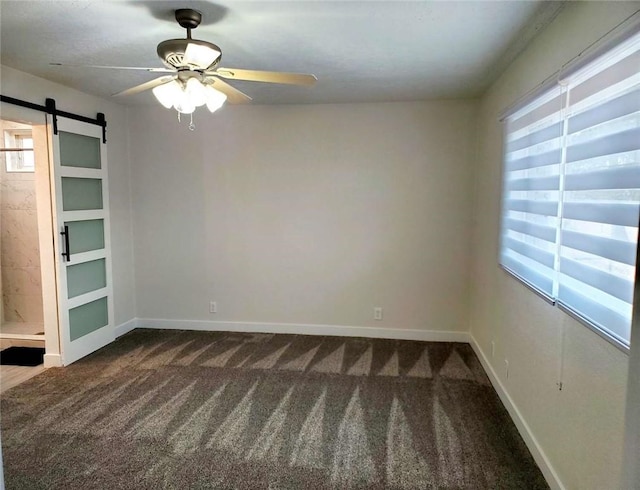 empty room with ceiling fan, carpet, and a barn door