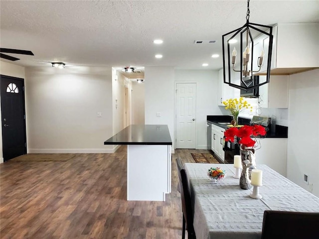 kitchen featuring dark wood-type flooring, a textured ceiling, pendant lighting, ceiling fan with notable chandelier, and white cabinets