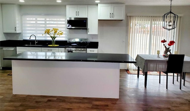 kitchen with an inviting chandelier, stainless steel appliances, decorative light fixtures, white cabinets, and sink