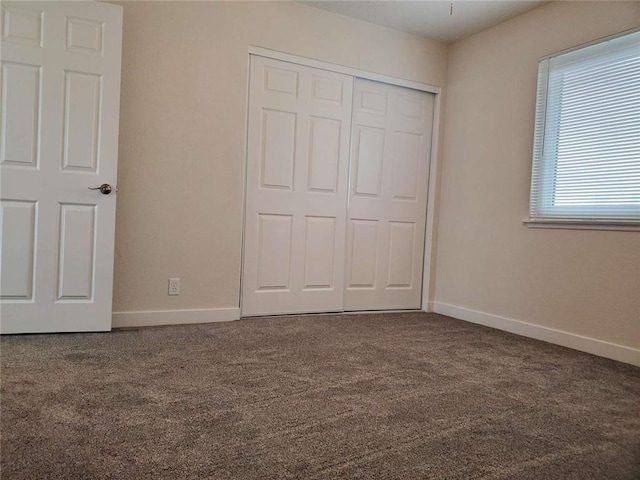 unfurnished bedroom featuring a closet and dark carpet