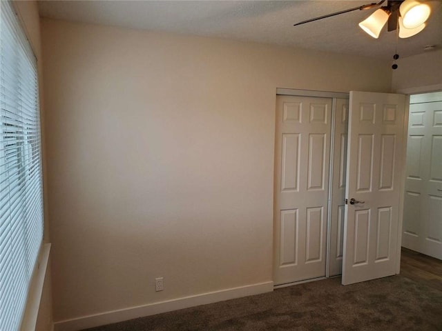 unfurnished bedroom featuring ceiling fan, a closet, and dark colored carpet