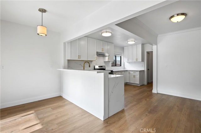 kitchen with backsplash, pendant lighting, stainless steel stove, kitchen peninsula, and white cabinetry