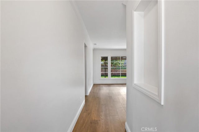 hallway featuring ornamental molding and hardwood / wood-style flooring