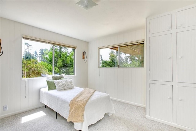 bedroom with light colored carpet and wood walls