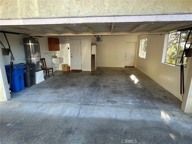 garage featuring sink, a garage door opener, and secured water heater