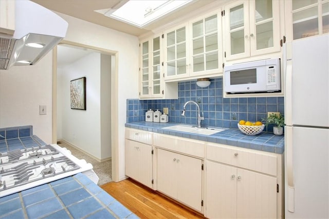 kitchen featuring tile countertops, extractor fan, white appliances, white cabinets, and sink