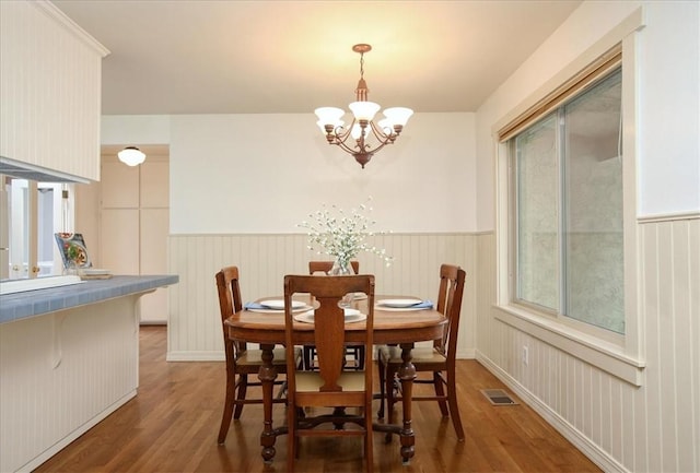 dining space with dark hardwood / wood-style floors and a notable chandelier