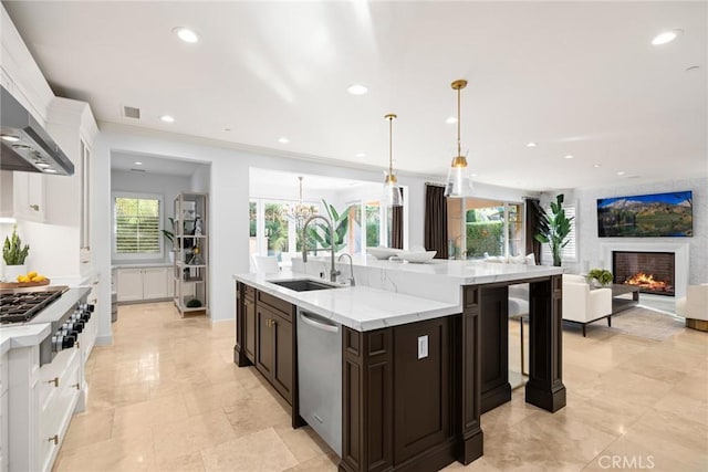 kitchen with stainless steel appliances, decorative light fixtures, light stone counters, dark brown cabinetry, and sink